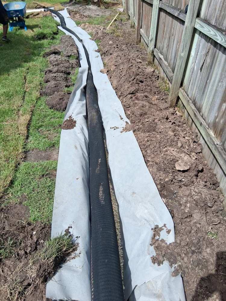 Perforated pipe on a washed-rock bed inside a fabric-lined trench