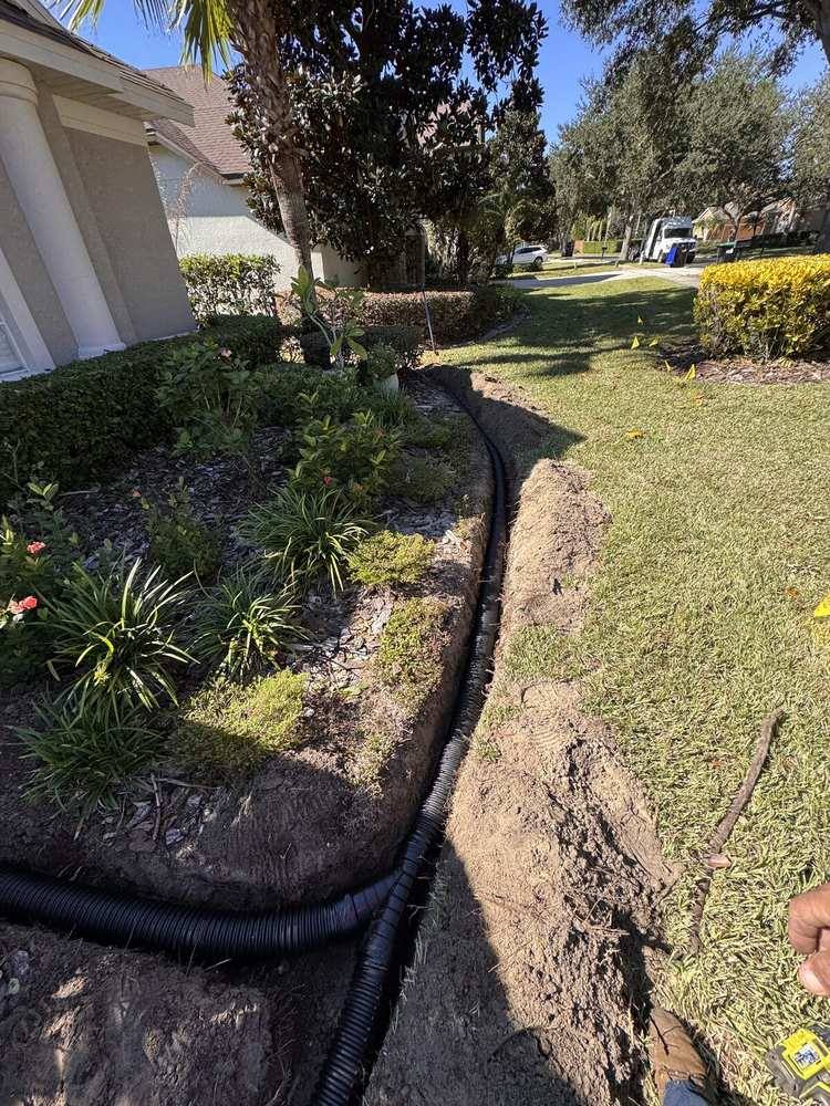 Drain pipe curving through a trench along a landscaped bed under a blue sky