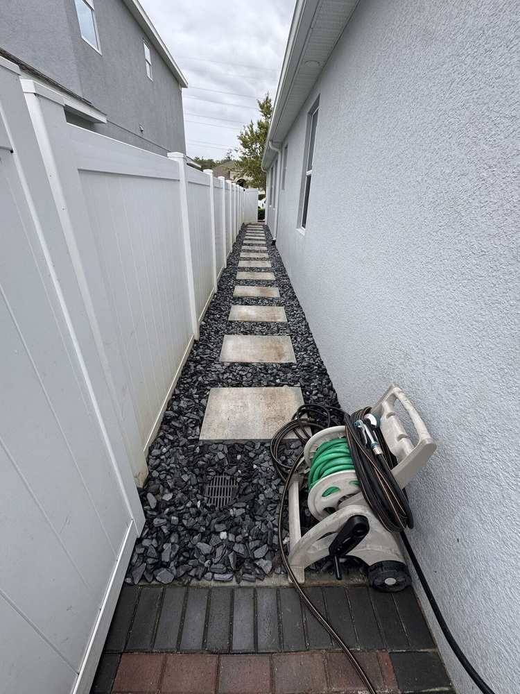 Finished side-yard drainage corridor with stepping stones over rock and a flush grate